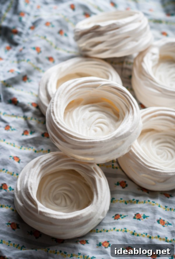 Homemade meringue cups are filled with vanilla bean whipped cream and roasted rhubarb. The perfect spring dessert! Baked Meringue Cups on Parchment Paper
