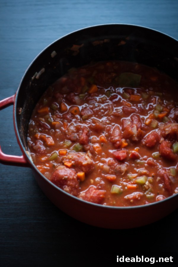 Hearty Cannellini Bolognese Spaghetti 4 Close-up of hearty cannellini bean bolognese sauce simmering in a deep red pot, rich in color and texture