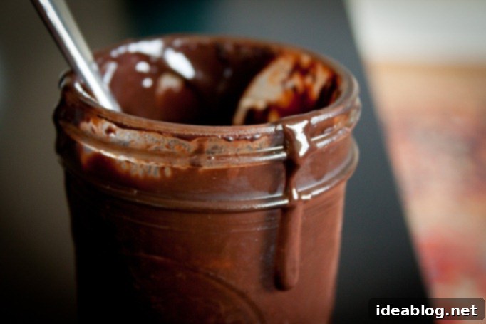 Wintermint Chocolate Elixir 3 Close-up of freshly made chocolate peppermint syrup in a glass jar with a metal lid, highlighting its smooth texture.