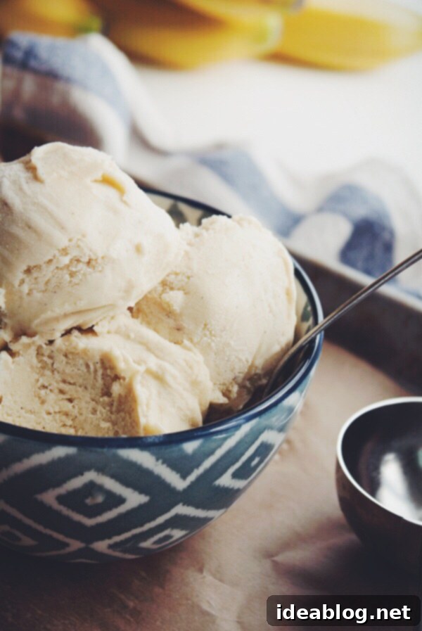 Golden Banana Bliss 6 Close-up of a serving of brown butter banana ice cream with a spoon, showing its smooth texture and vanilla bean flecks
