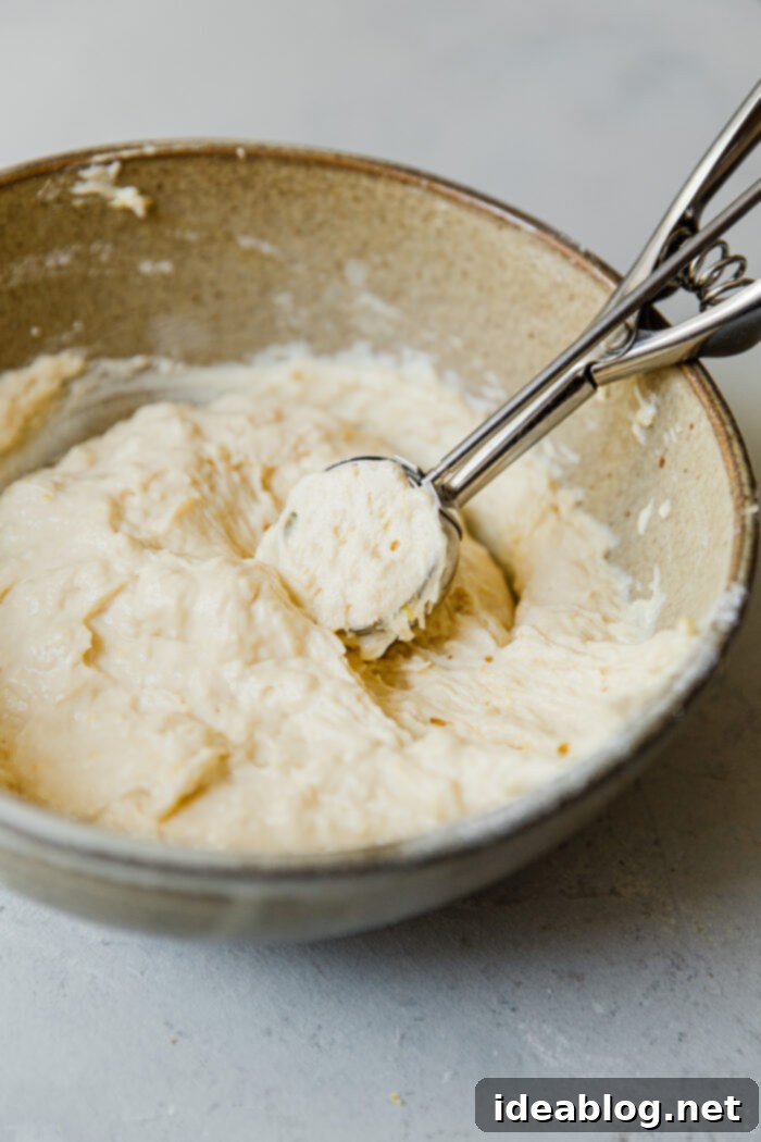 Lemon Cardamom Ricotta Donuts 10 Using a small cookie scoop to drop ricotta donut batter into hot frying oil, illustrating the frying process.