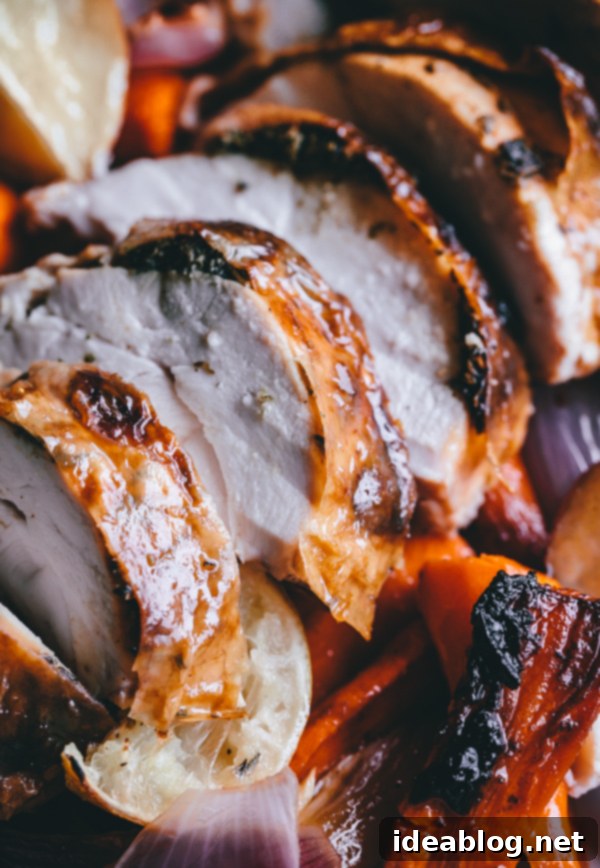 Effortless Herb-Roasted Chicken with Seasonal Vegetables 5 A carving board with a juicy, perfectly sliced herb roasted chicken, revealing tender meat and crispy skin, served alongside golden-brown roasted vegetables.