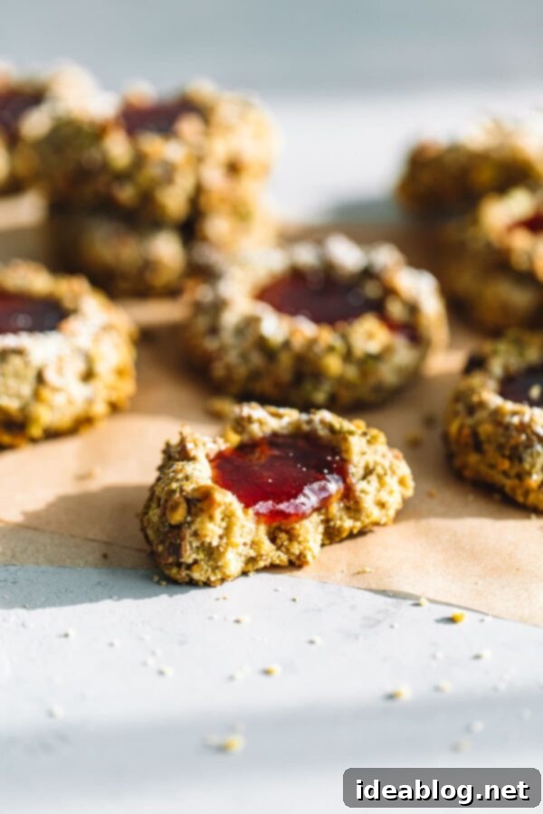 Jam-Filled Pistachio Thumbprint Cookies 3 Close-up of Raspberry Jam Thumbprint Cookies with crunchy pistachio coating