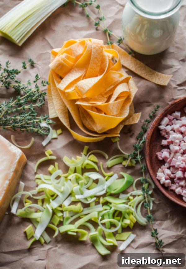 Key ingredients for Creamy Leek and Pancetta Pappardelle Pasta: leeks, pancetta, cream, pasta Ingredients for Creamy Leek and Pancetta Pappardelle Pasta laid out on a table
