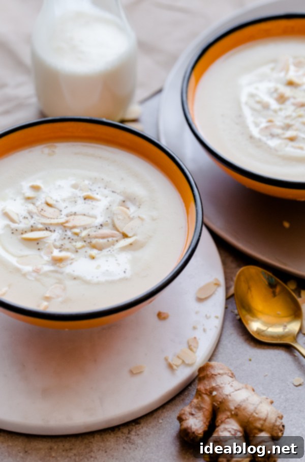 Warming Parsnip Ginger Soup 2 Rich and creamy parsnip and ginger soup, garnished with fresh herbs and toasted nuts in a rustic bowl.