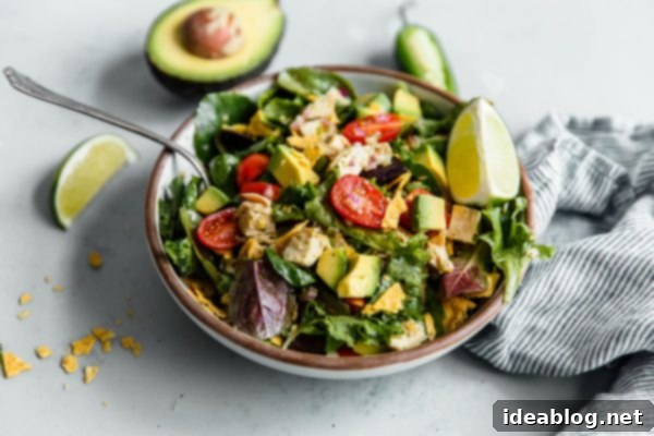 Guacamole Greens Salad with Cilantro Lime Jalapeño Vinaigrette--an easy, incredibly filling healthy main course salad tossed with a homemade cilantro lime vinaigrette! #salad #guacamole #abeautifulplate #chicken #recipe #avocado Guacamole Greens Salad served on a white plate