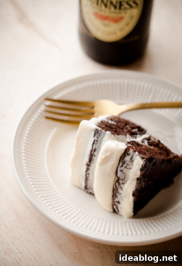 Guiness Stout Cake with Bailey's Cream Cheese Frosting - a festive St. Patrick's Day dessert! Dark, spiced Guinness stout cake topped with a homemade cream cheese frosting infused with Bailey's Irish cream. #cake #stpatricksday #dessert #holiday #recipe #abeautifulplate.com A slice of Guinness Stout Cake with Bailey's Cream Cheese Frosting, ready to enjoy