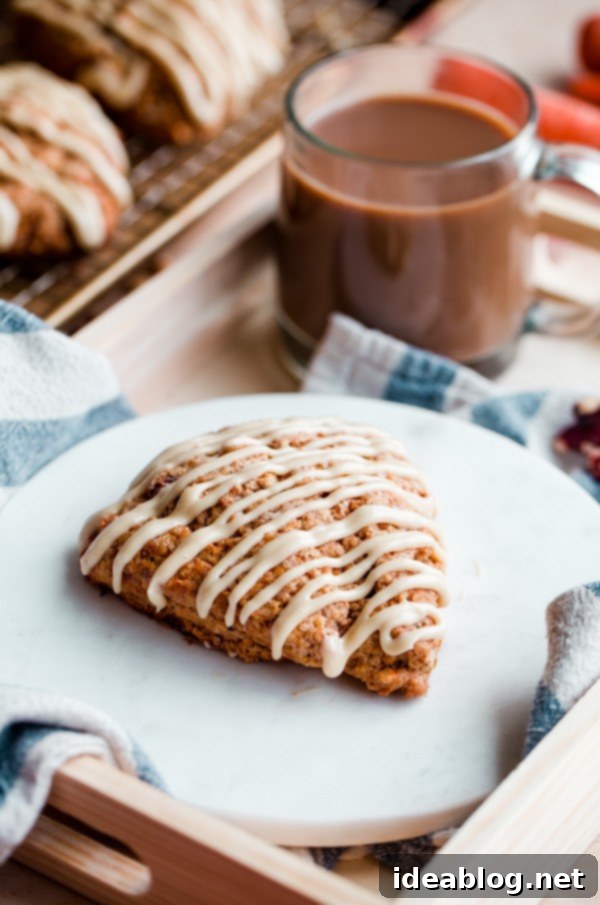 Spiced Carrot Cake Scones with Maple Cream Cheese Glaze 6 A warm Carrot Cake Scone with maple cream cheese glaze, accompanied by a steaming cup of coffee, perfect for breakfast