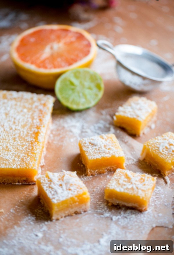 Bright Citrus Coconut Shortbread 2 Four Citrus Coconut Shortbread Bars with a rich, golden curd layer and a sprinkle of powdered sugar, presented on a white plate