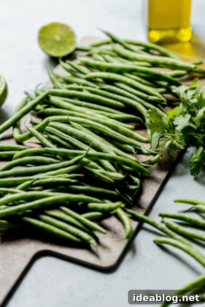 Fire-Kissed Green Beans with Zesty Cilantro Dressing 4 Raw green beans and fresh cilantro lime vinaigrette ingredients laid out on a cutting board, prior to preparation.