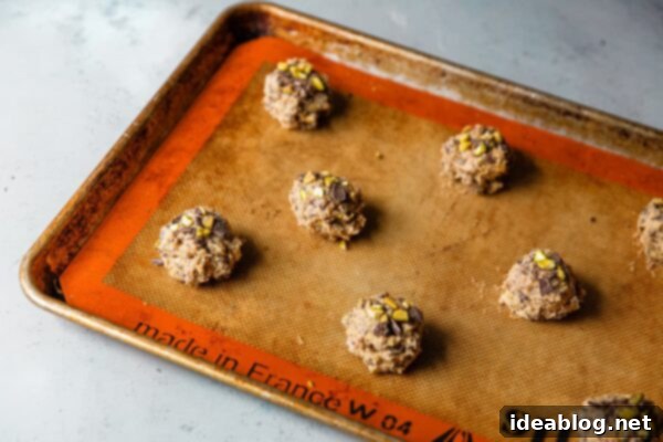 Zesty Orange Pistachio Chocolate Chunk Cookies 12 Orange Pistachio Dark Chocolate Chunk Cookie Dough Scoops on a baking sheet
