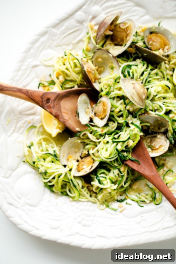 Zucchini Pasta with Garlic Clam Sauce. An EASY, healthy dinner recipe made with zucchini noodles. Less than 250 calories per serving! #abeautifulplate #glutenfree #clam #pasta #zoodles #recipe Close-up of Zucchini Pasta with Garlic Clam Sauce, garnished with fresh parsley and lemon wedges