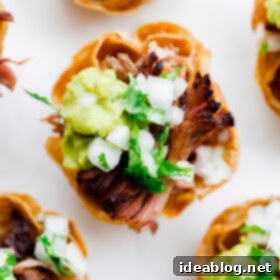 Crispy Slow Cooker Carnitas Taco Bites 3 Close-up of a single Slow Cooker Carnitas Taco Bite with guacamole and cilantro.