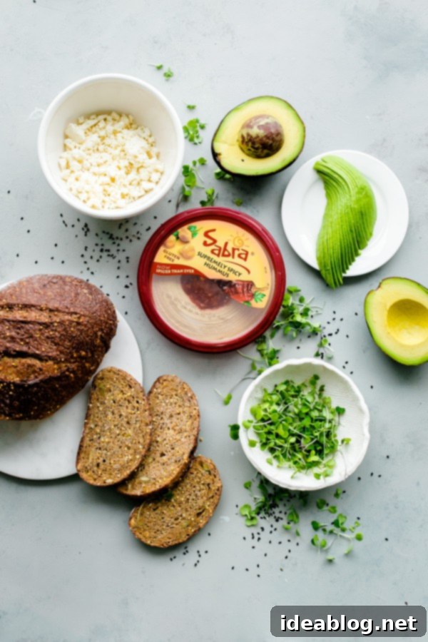 Spicy Hummus Avocado Toast with Feta. An easy vegetarian snack with a spicy kick! #abeautifulplate #vegetarian #feta #hummus #toast #recipe #avocado Ingredients for Spicy Hummus Avocado Toast, including hummus, avocado, feta, and microgreens