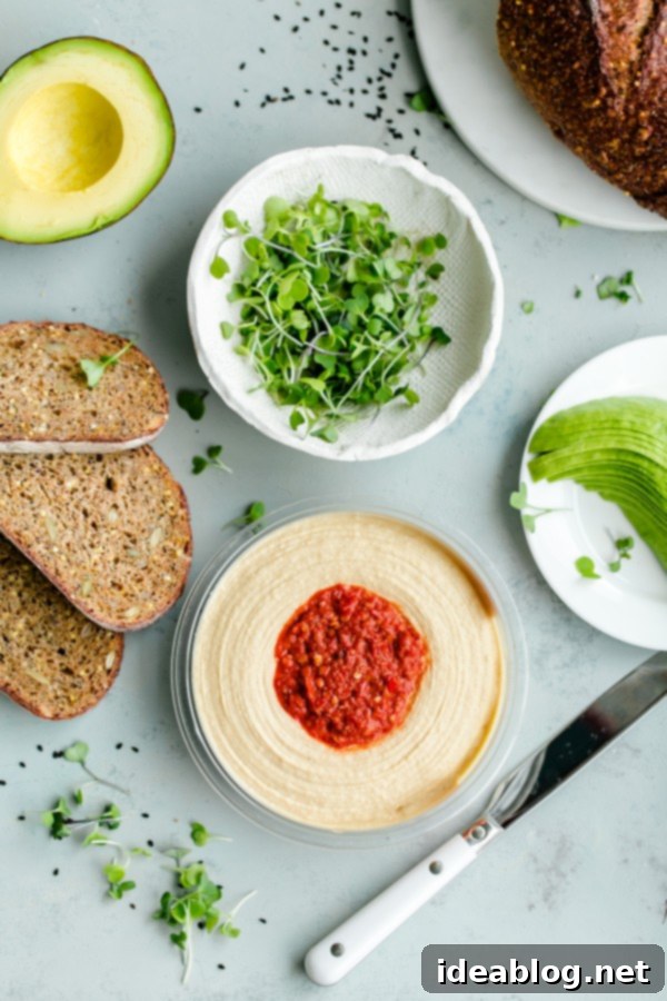 Spicy Hummus Avocado Toast with Feta. An easy vegetarian snack with a spicy kick! #abeautifulplate #vegetarian #feta #hummus #toast #recipe #avocado Hummus, avocado, feta, and microgreens laid out for Spicy Hummus Avocado Toast
