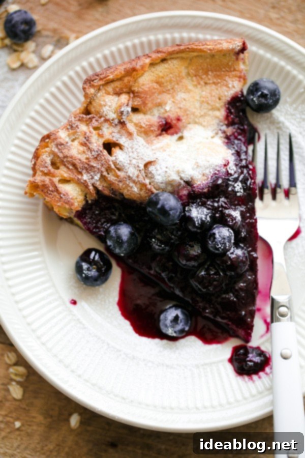 Delicious Gluten-Free Dutch Baby served generously with homemade blueberry maple syrup Close-up of a Gluten-Free Dutch Baby slice with melted butter, fresh blueberries, and sweet syrup