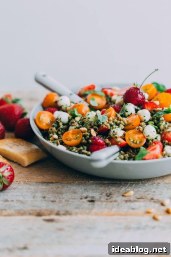 Strawberry Caprese Farro Salad. Hearty farro is tossed with homemade pesto, strawberries, tomatoes, and mozzarella cheese to create this beautiful summer grain salad! #salad #abeautifulplate #recipe #farro #caprese #mozzarella Strawberry Caprese Farro Salad