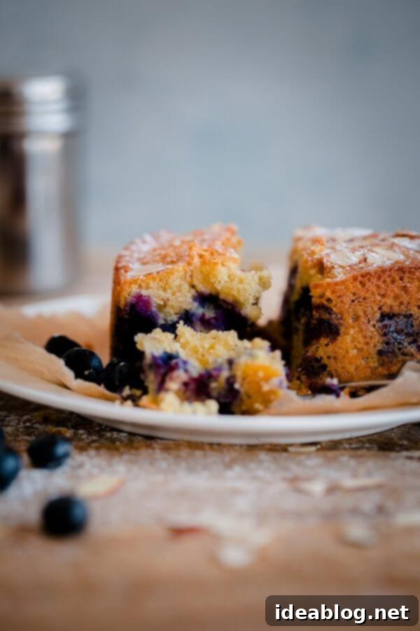 Artisan Blueberry Almond Tea Cake 6 A slice of Blueberry Almond Tea Cake on a wooden board, with a sprig of fresh mint.
