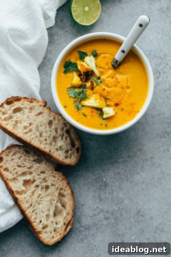 Healthy Roasted Cauliflower Soup with Coconut Milk Creamy Roasted Cauliflower Soup with Coconut and Turmeric in a bowl, garnished