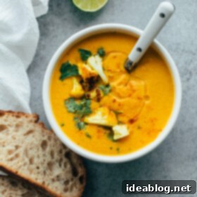 Velvety Roasted Cauliflower Soup: Coconut Turmeric Delight 4 Healthy Roasted Cauliflower Soup with Coconut and Turmeric in a white bowl, garnished