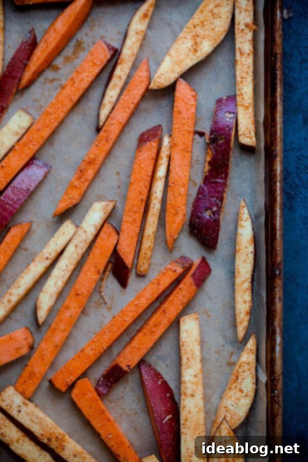 Golden Spiced Sweet Potato Fries with Creamy Garlic Aioli 6 A close-up of a serving of baked sweet potato fries sprinkled with fresh parsley, alongside a bowl of garlic aioli, ready for dipping.