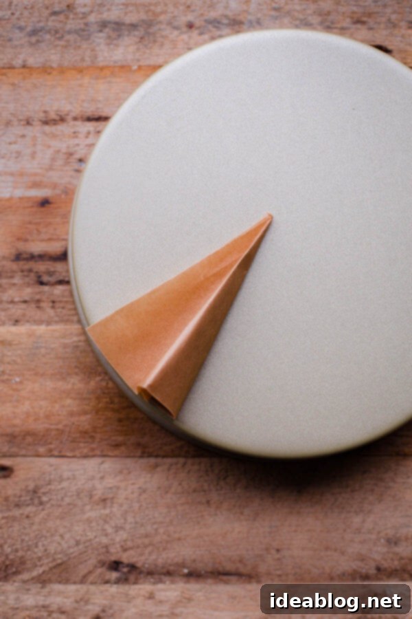 Flawless Cake Release: Parchment Lining Any Pan 11 A pair of scissors cuts the parchment paper along the curve of the inverted cake pan, creating a perfect round.