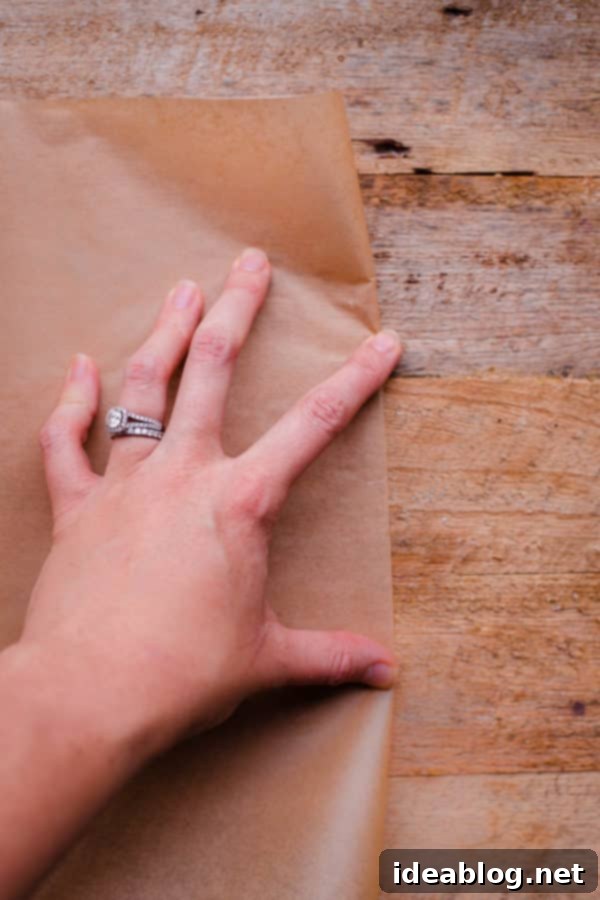 Flawless Cake Release: Parchment Lining Any Pan 4 First fold: A rectangular piece of parchment paper is neatly folded in half, creating a crisp crease down the middle.