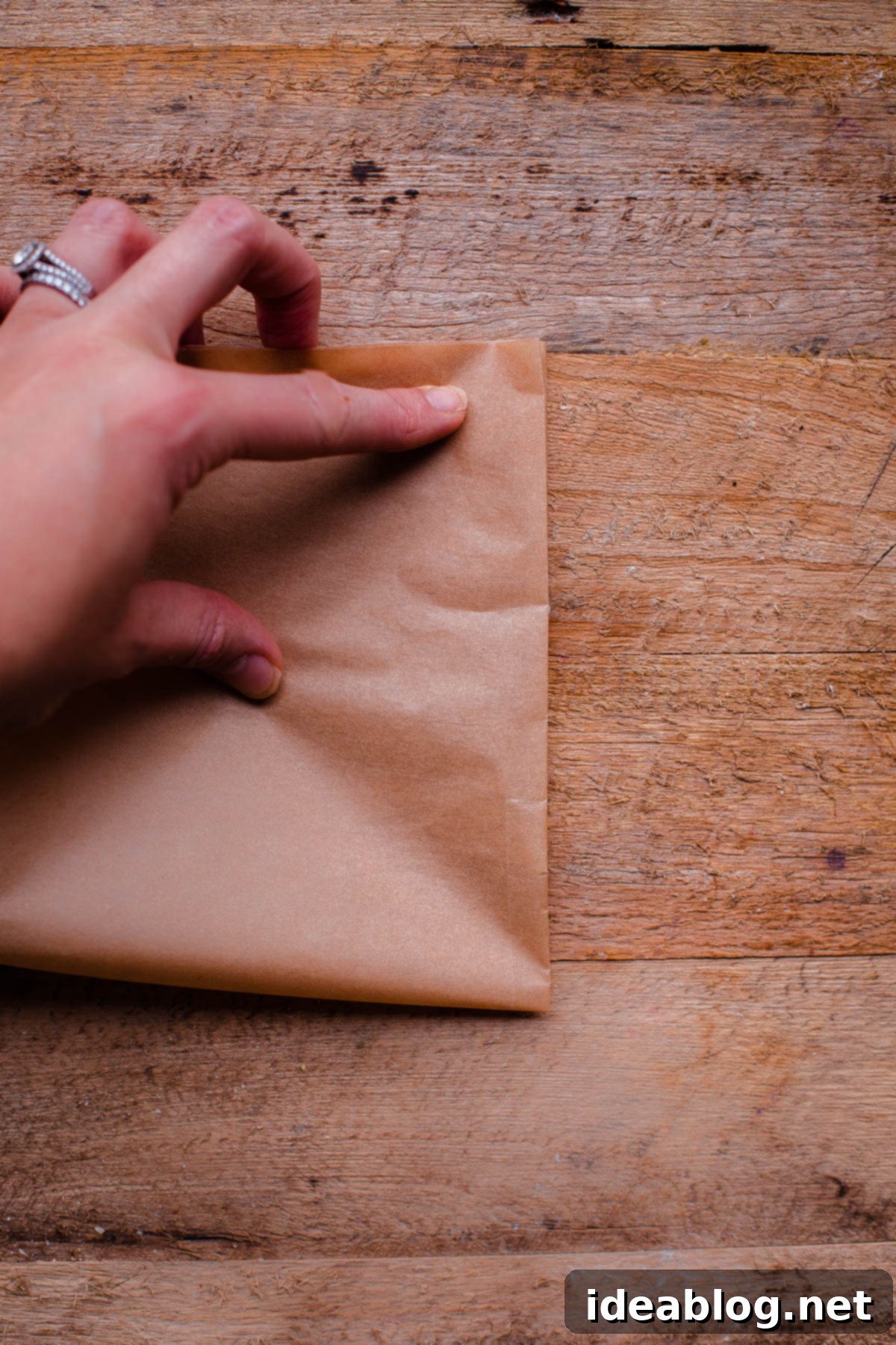 Flawless Cake Release: Parchment Lining Any Pan 6 The folded parchment paper, now a compact square, is shown before being folded into a triangle.