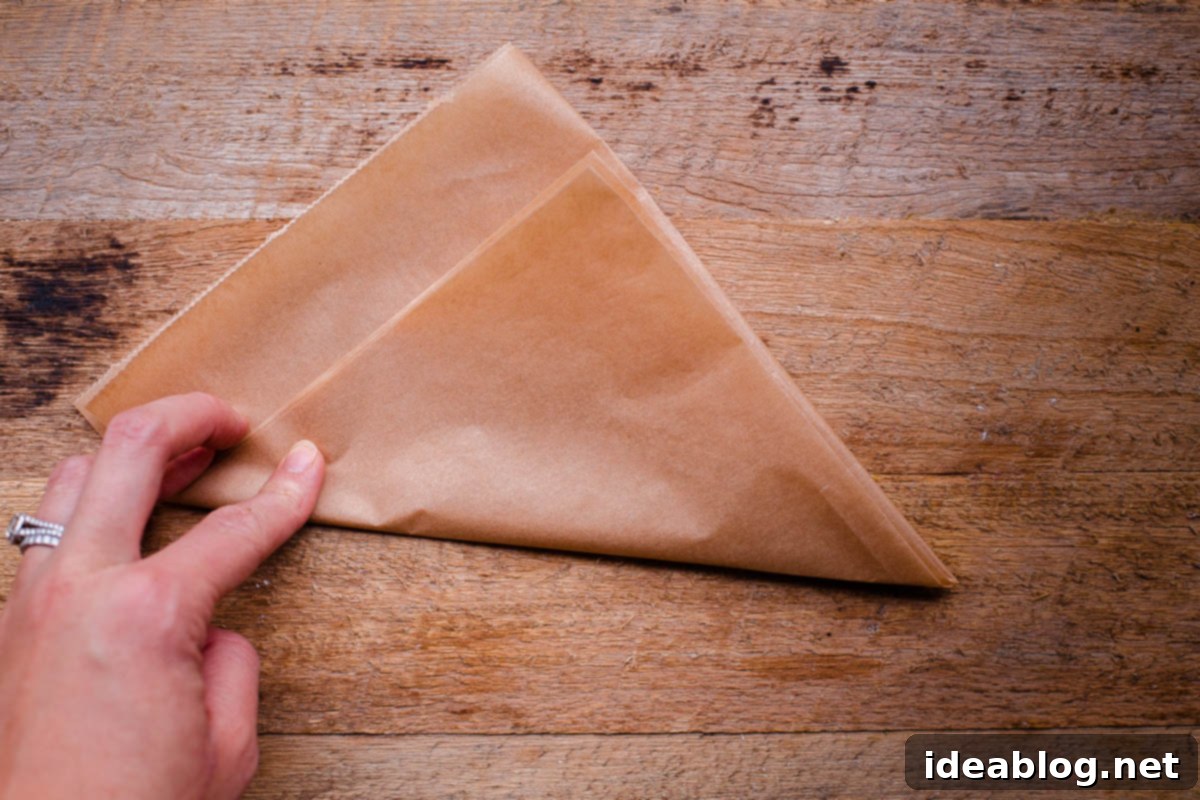 Flawless Cake Release: Parchment Lining Any Pan 7 The square of parchment paper is now folded diagonally into a perfect triangle shape, ready for further folding.