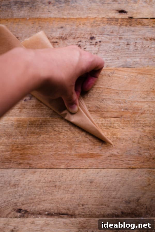 Flawless Cake Release: Parchment Lining Any Pan 8 The parchment paper triangle is folded in half again, making it smaller and denser, crucial for a precise cut.