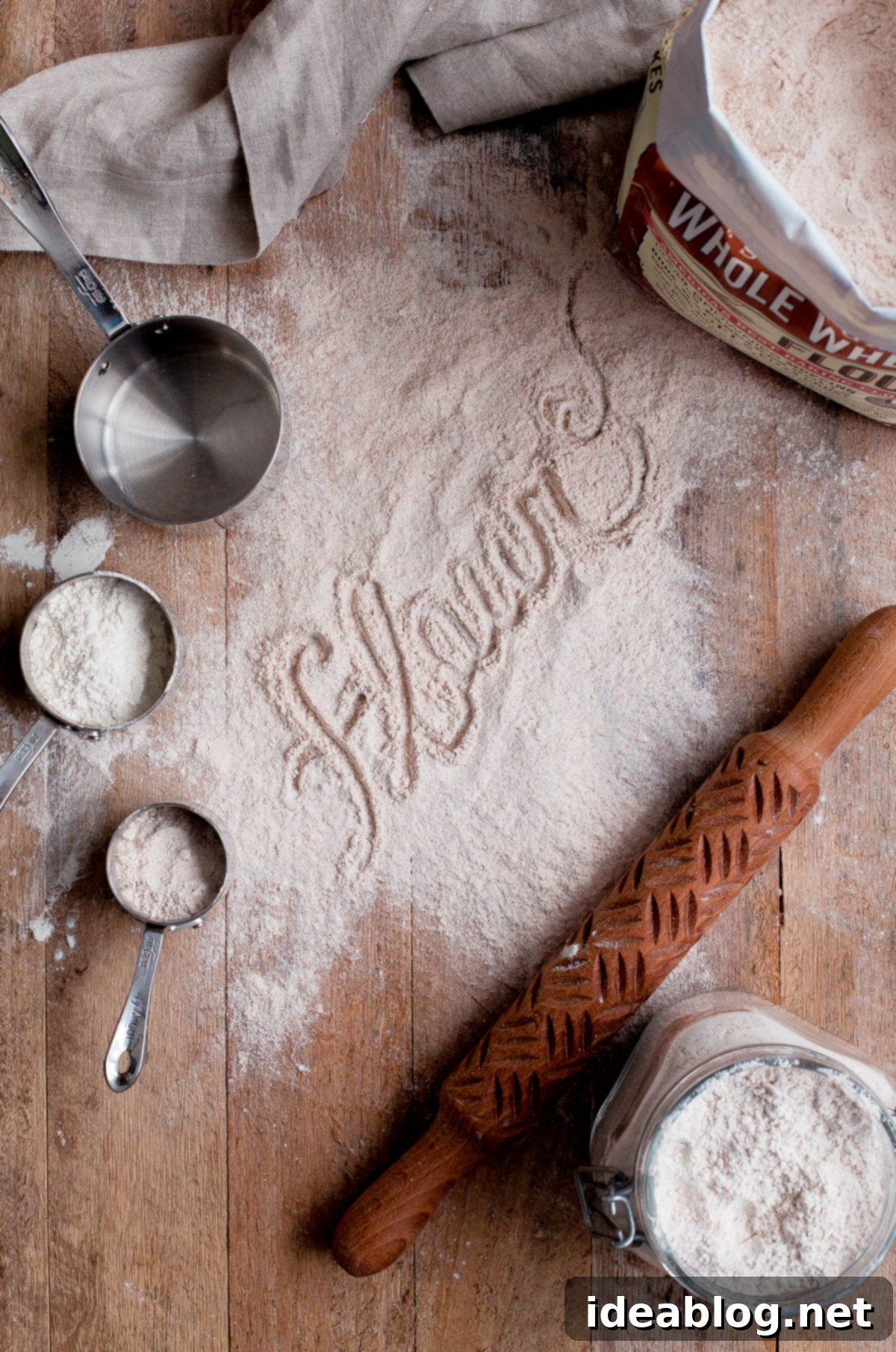 Flour 101: Different Types of Flours for Baking and the Fundamental Differences Between Them. An incredibly helpful baking reference post! Various types of flour neatly arranged on a wooden board with measuring spoons.