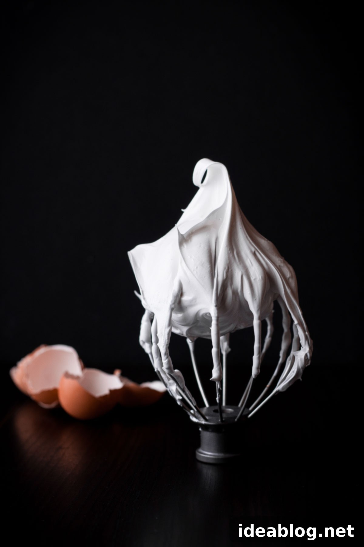 Perfectly whipped meringue on a whisk attachment, ready for shaping into a pavlova shell. Meringue mixture on a whisk attachment showing stiff peaks