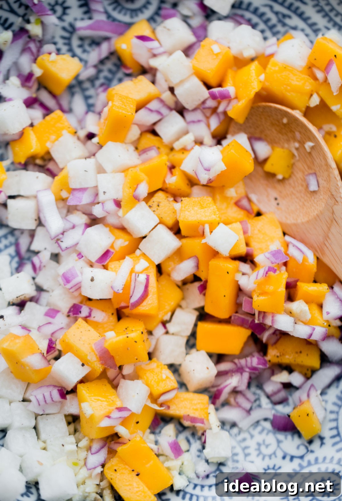The foundational mix for Tropical Mango Guacamole: colorful cubes of mango, crisp jicama, and finely chopped red onion, seasoned and ready for avocado. Freshly diced mango, jicama, and red onion mixed in a bowl, awaiting the creamy avocado base for the tropical guacamole.