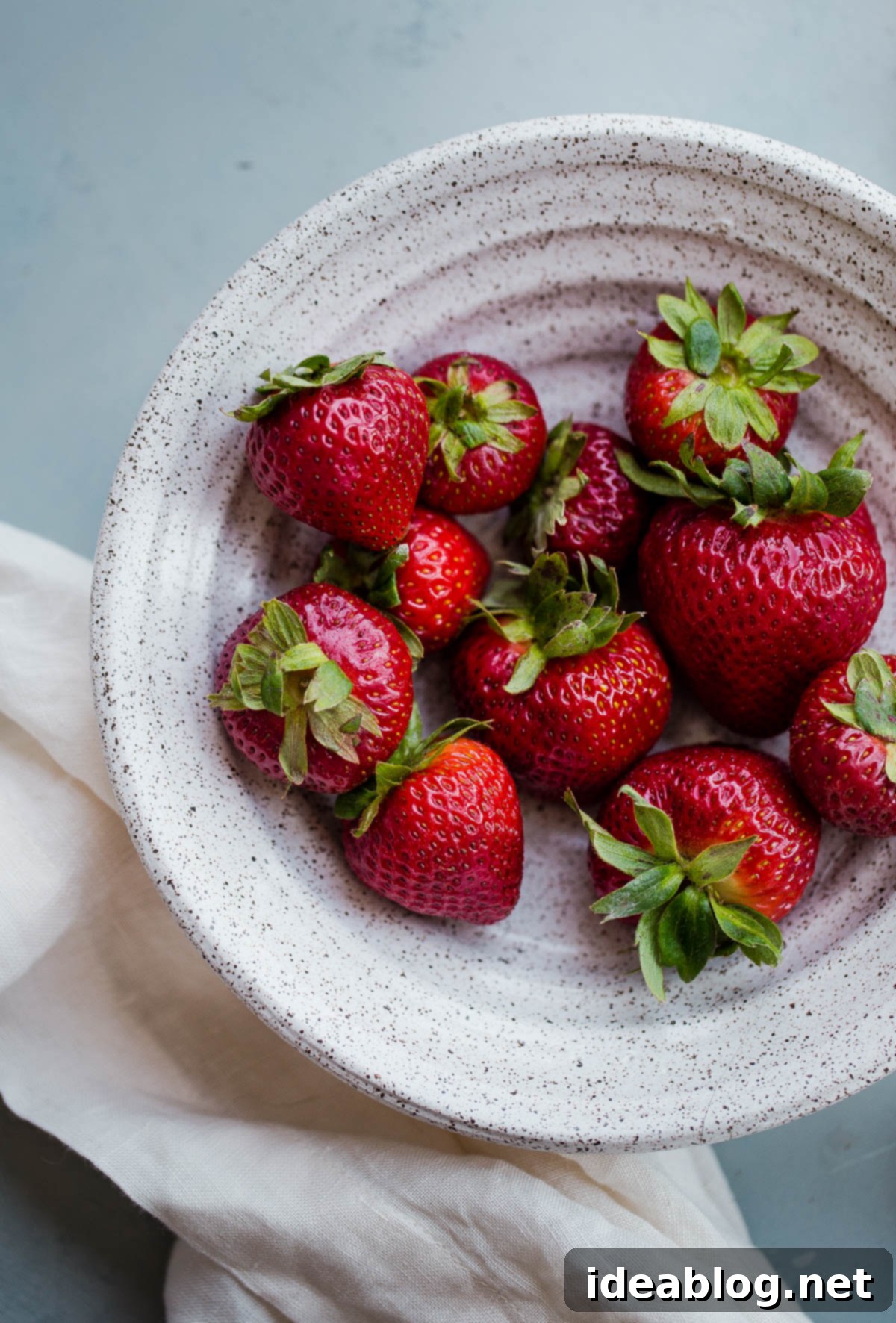 Strawberry Elderflower Sparkler - a refreshing summer prosecco cocktail infused with fresh strawberry puree, elderflower liqueur, and vodka. Fresh, ripe strawberries in a bowl, perfect for making homemade puree for cocktails