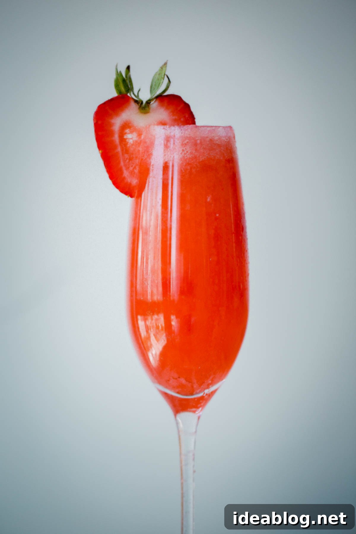 Strawberry Elderflower Sparkler - a refreshing summer prosecco cocktail infused with fresh strawberry puree, elderflower liqueur, and vodka. Strawberry Elderflower Sparkler served in a champagne flute, garnished with a fresh strawberry slice