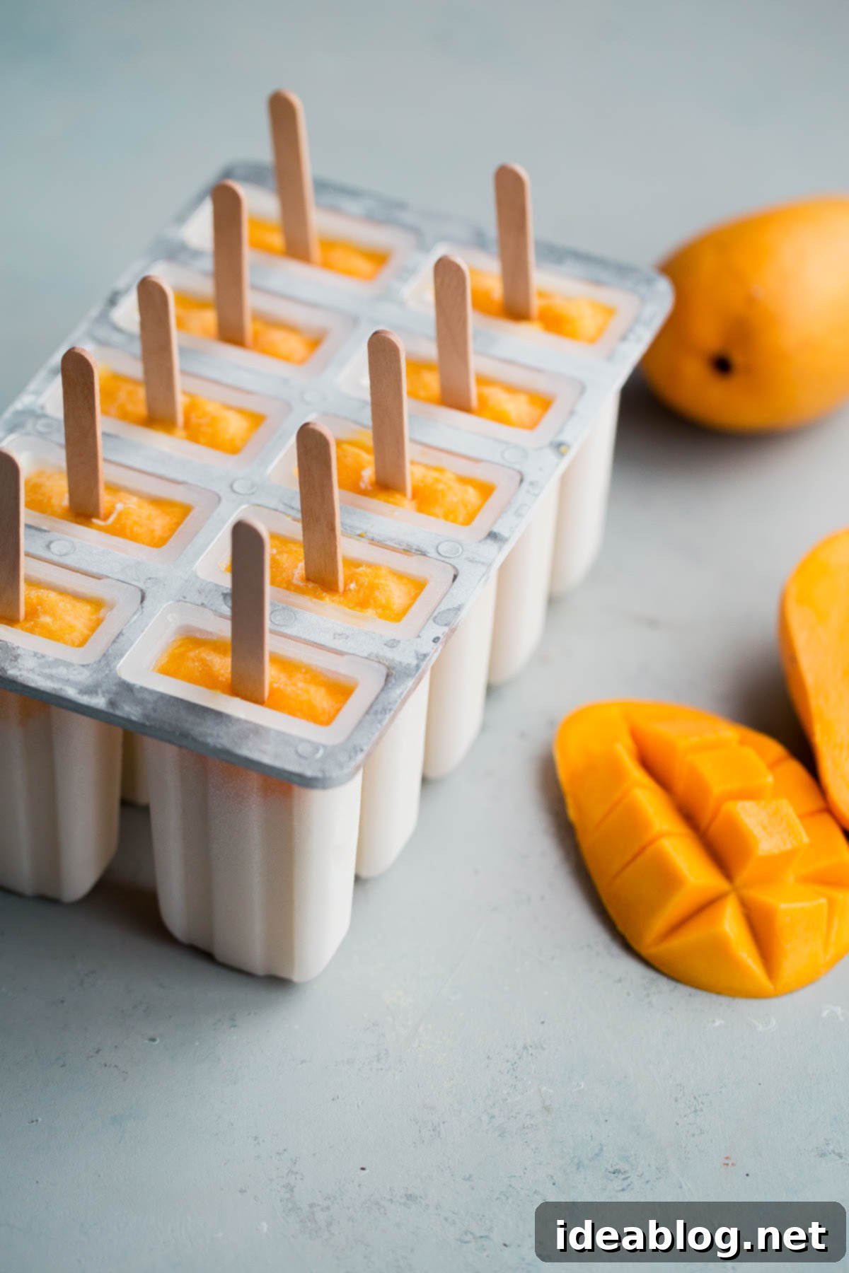 Mango Lassi Popsicles - healthy mango popsicles made with Greek yogurt, coconut milk, and fresh mango! Naturally sweetened.  Mango Lassi Popsicles chilling in a silicone mold, showcasing the layered fruit and yogurt base.