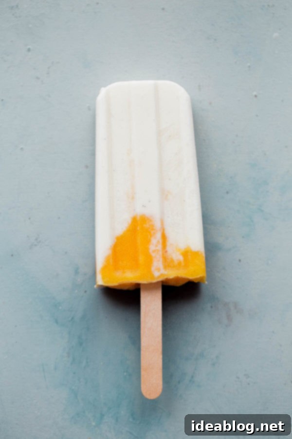 Sunshine Mango Lassi Pops 3 Close-up of a refreshing healthy mango lassi popsicle, showcasing its vibrant layers.