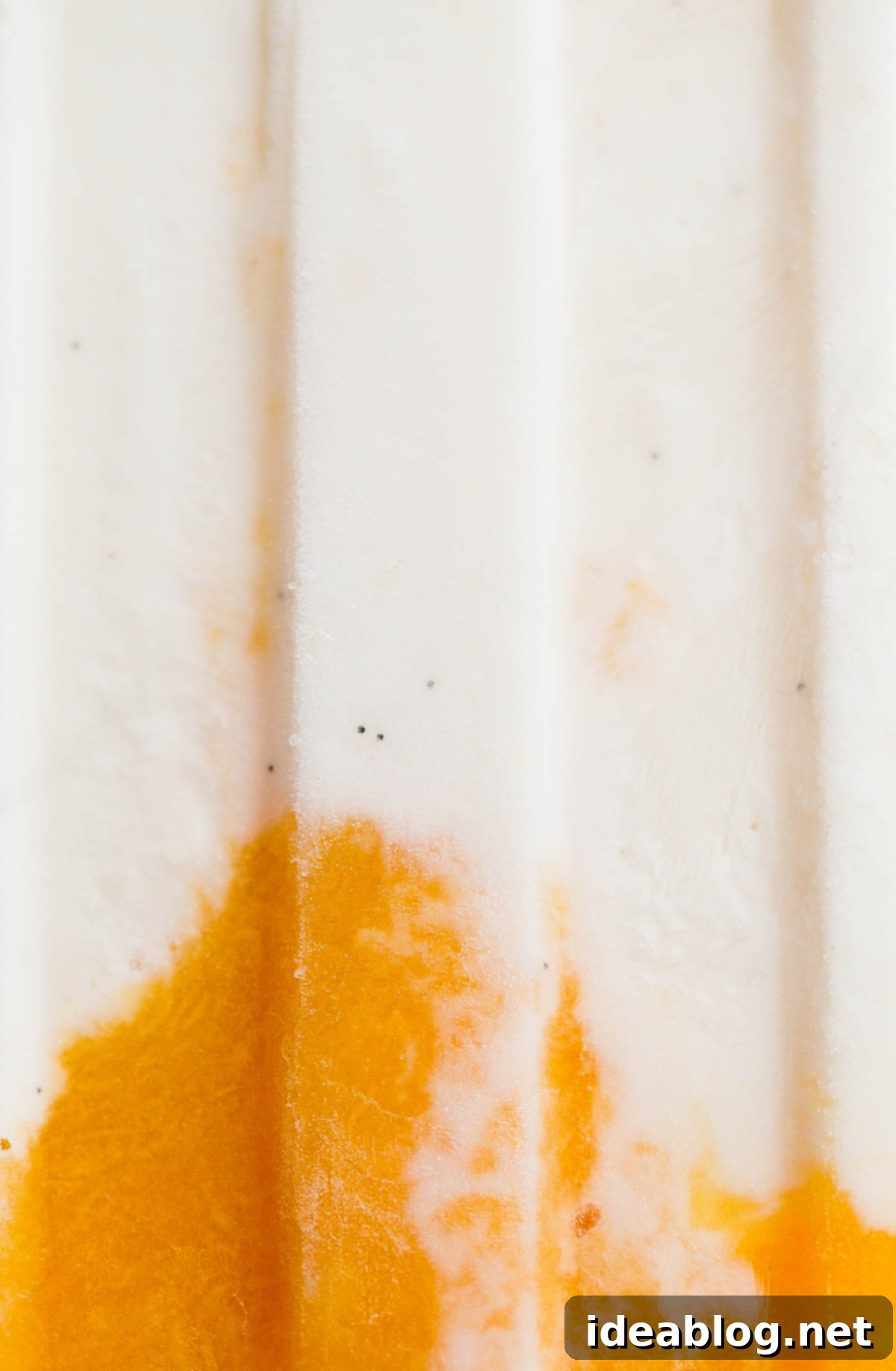 Mango Lassi Popsicles - healthy mango popsicles made with Greek yogurt, coconut milk, and fresh mango! Naturally sweetened.  Close-up of a single mango popsicle, vibrant orange, ready to be enjoyed.