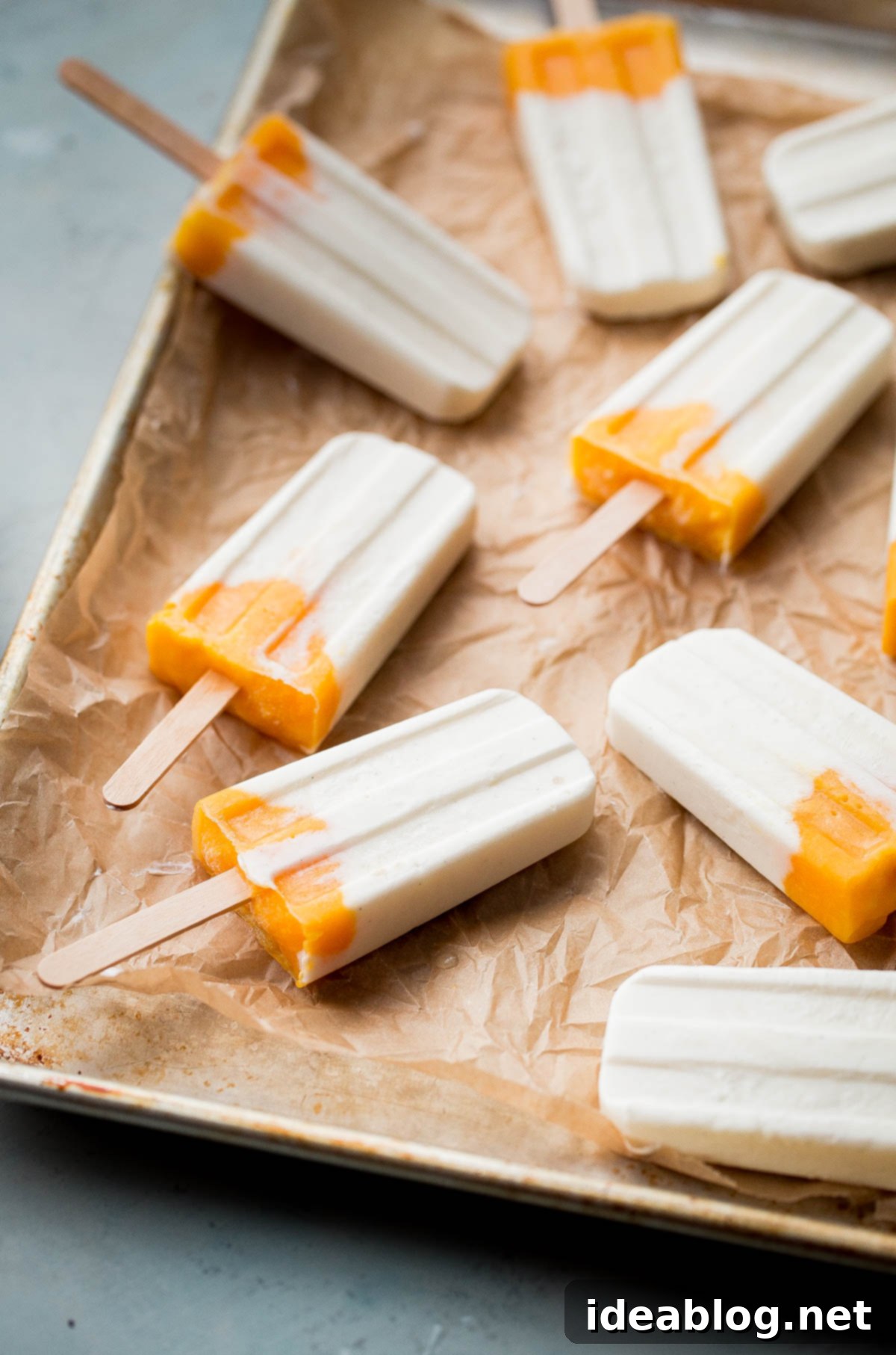 Mango Lassi Popsicles - healthy mango popsicles made with Greek yogurt, coconut milk, and fresh mango! Naturally sweetened.  A tray of freshly made mango lassi popsicles, showcasing their beautiful two-tone layers and ready for the freezer.