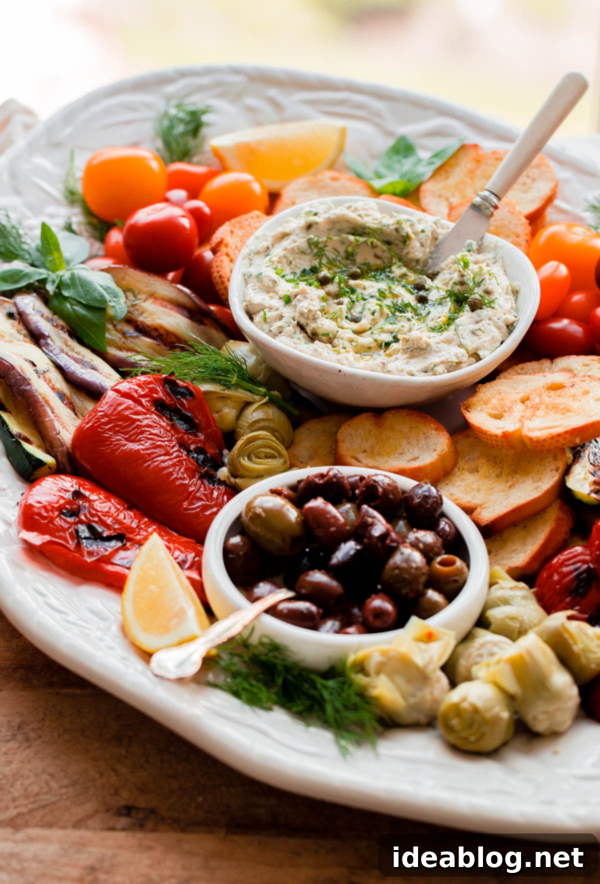 Complete Italian Antipasto Platter featuring delicious Tuna Crostini Full Italian Antipasto Platter with Tuna Crostini, grilled vegetables, olives, and artichokes.