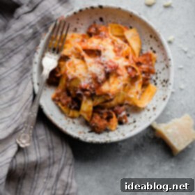 Deep-Flavor Bolognese Ragu 8 A bowl of slow cooker bolognese pasta garnished with fresh herbs and grated cheese.