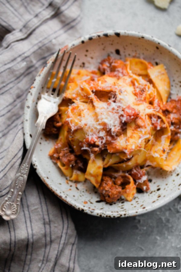 Deep-Flavor Bolognese Ragu 7 Hearty slow cooker bolognese pasta served on a white plate, topped with fresh basil.