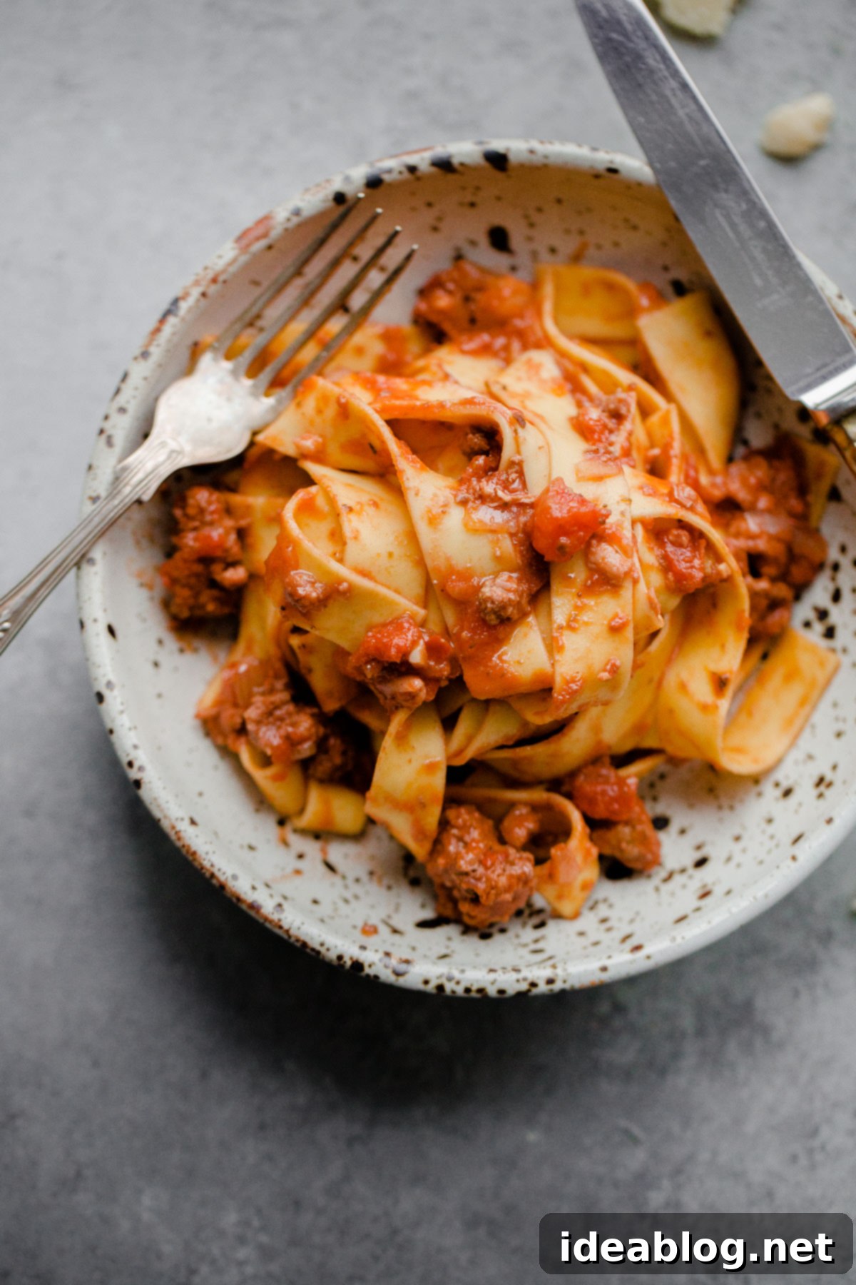 Slow Cooker Bolognese Pasta A beautifully plated bowl of slow cooker bolognese pasta with a generous sprinkle of Parmesan.