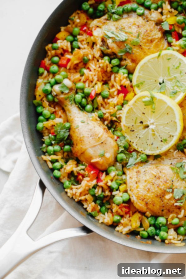 Arroz Con Pollo - an easy, comforting ONE pot meal that comes together in less than 45 minutes. This classic Spanish and Mexican dish is made with rice, chicken, bell peppers, and spices. Close-up of Arroz Con Pollo in a non-stick skillet, showcasing perfectly seared chicken and rice.