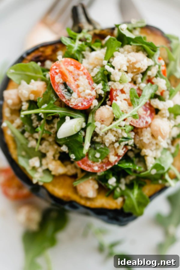 Mediterranean Quinoa Salad Stuffed Acorn Squash - roasted acorn squash filled with a vegetarian quinoa salad packed with arugula, tomatoes, scallions, and an easy lemon vinaigrette. A delicious vegetarian recipe. Roasted acorn squash half, golden brown and tender, sitting on a baking sheet, ready for its quinoa filling.