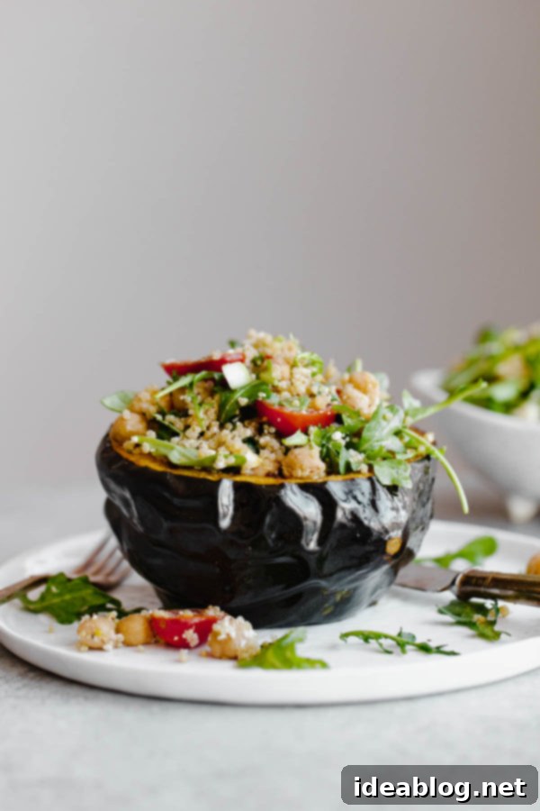 Mediterranean Quinoa Salad Stuffed Acorn Squash - roasted acorn squash filled with a vegetarian quinoa salad packed with arugula, tomatoes, scallions, and an easy lemon vinaigrette. A delicious vegetarian recipe. Two roasted acorn squash halves generously stuffed with colorful Mediterranean quinoa salad, drizzled with tahini, on a rustic serving board.