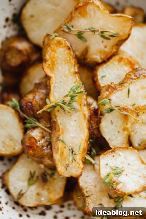 Perfectly roasted sunchoke slices, also known as Jerusalem artichokes, seasoned with fresh herbs for a healthy side dish. Close-up of roasted sunchoke slices with herbs in a bowl