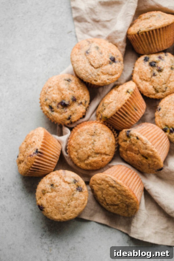 EASY Blueberry Muffins - this delicious whole wheat blueberry muffins recipe that comes together quickly and is made with coconut oil, buttermilk, and wild frozen blueberries. #blueberries #buttermilk #wholewheat #muffins #abeautifulplate #coconutoil #berries Easy Whole Wheat Blueberry Muffins on a wooden board