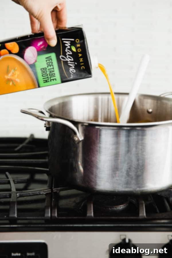 Person Pouring Vegetable Broth into a Pot of Vegetarian Chili