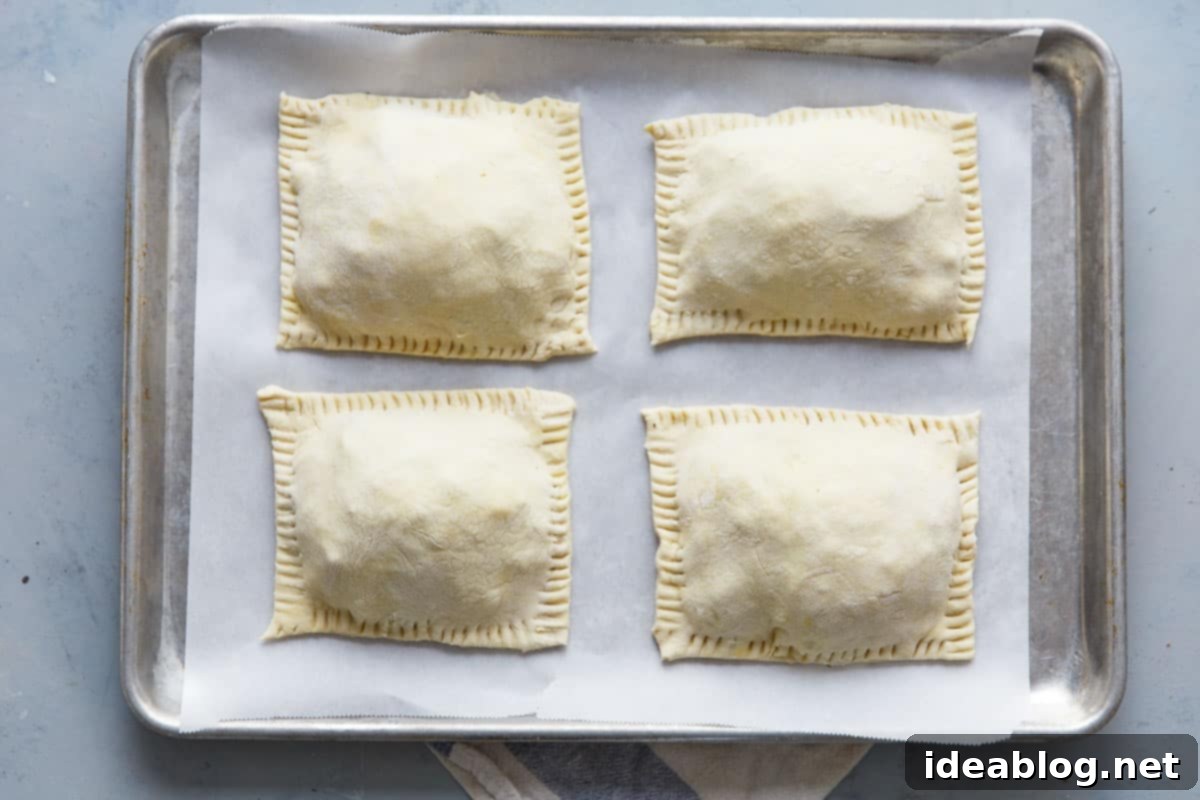 Golden Potato Leek Cornish Pasty 9 Assembled potato leek pasties on a sheet pan with crimped edges and egg wash, ready for baking